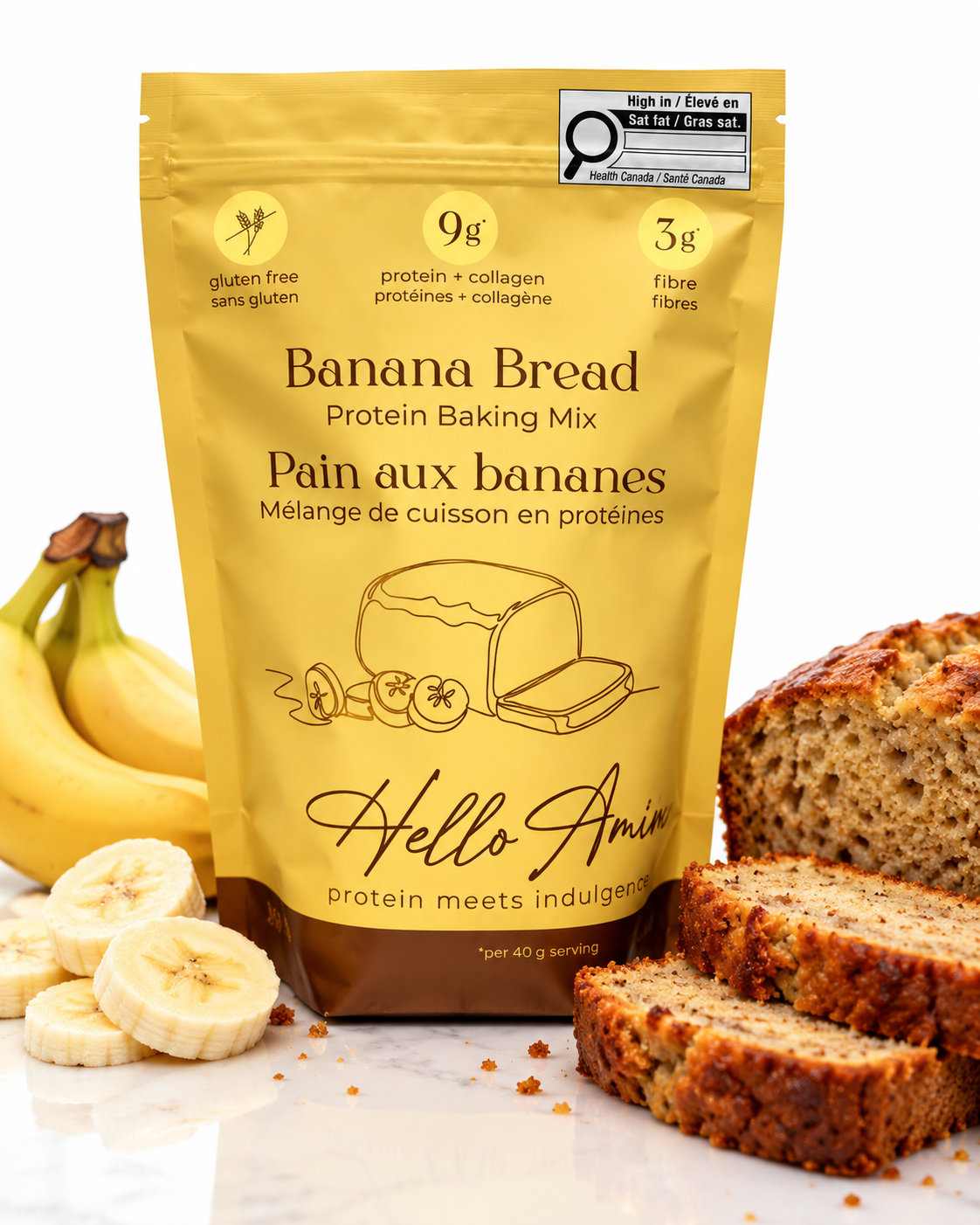 A stand-up pouch of Hello Amin Banana Bread Protein Baking Mix stands on a white marble surface with bananas, banana slices, and sliced banana bread around it. The pouch is golden yellow with black and brown text, and a Hello Amin brand logo is clearly visible.