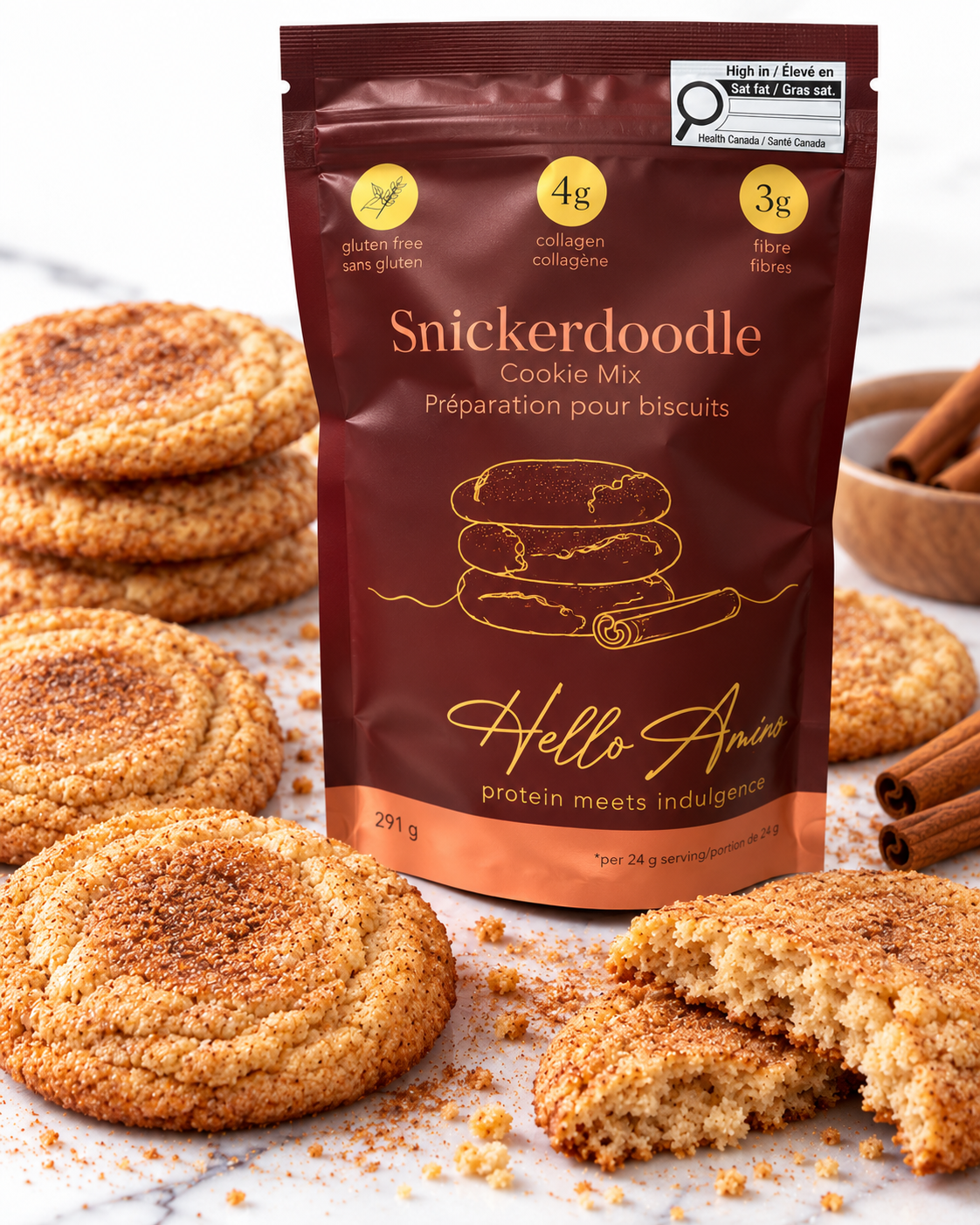 A stand-up pouch of HelloAmino Snickerdoodle Cookie Mix stands on a marble surface surrounded by cinnamon-sugar-coated cookies, with a whole cookie and a broken piece in front. The package is dark brown with gold and white text and graphics, and the scene is styled with cinnamon sticks and cookies.
